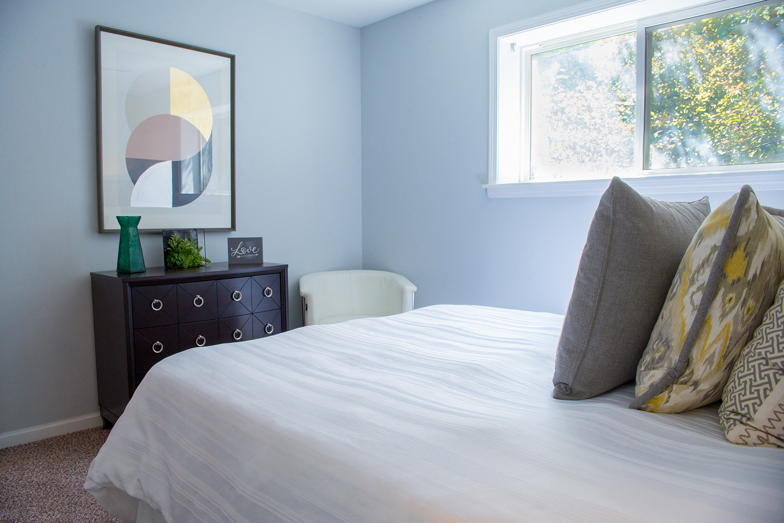 A bedroom with a bed, nightstand, and a painting on the wall.