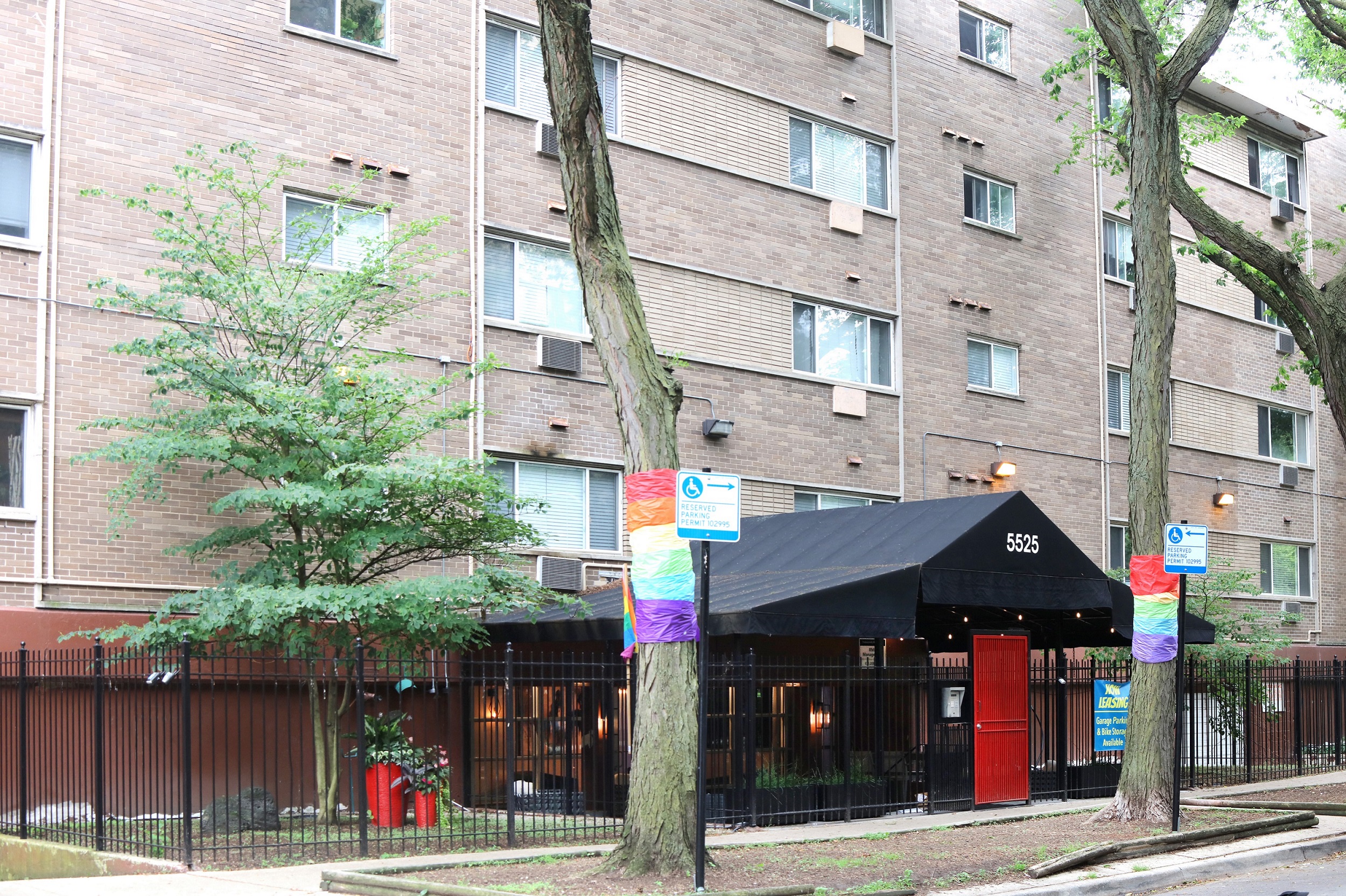 A building with a black awning and a rainbow flag on it.