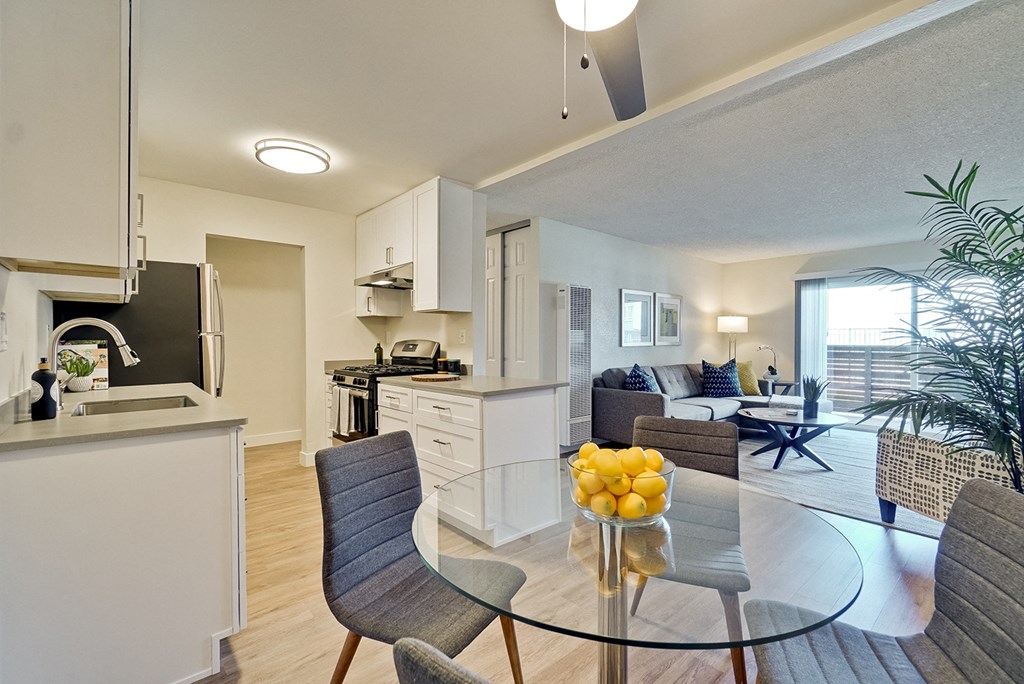 Apartments for Rent in Fremont CA - Metro Fremont - Glass Dining Room Table with Grey Chairs, Decorative Fruit Center Piece, Open Floor Plan, and Wood-Style Flooring