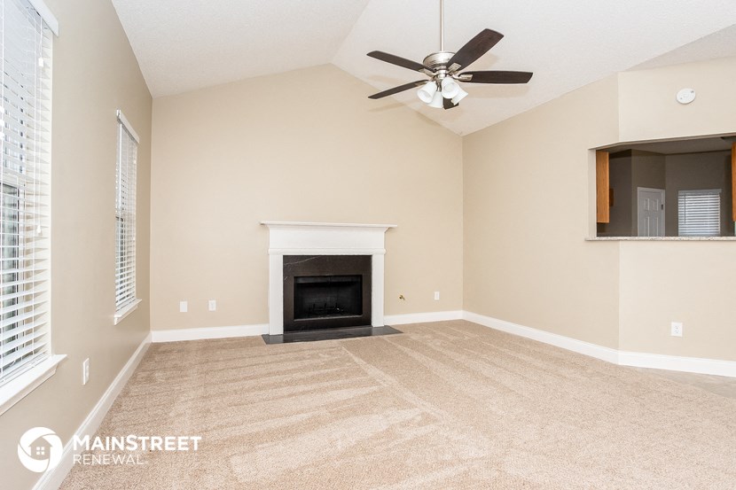a living room with a fireplace and a ceiling fan