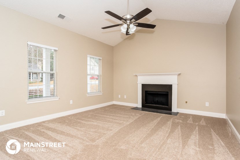a living room with a fireplace and a ceiling fan