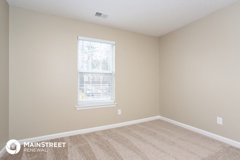 the living room of a home with carpet and a window