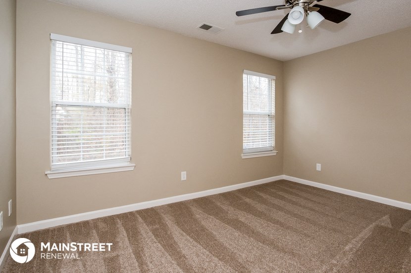 an empty room with a ceiling fan and two windows