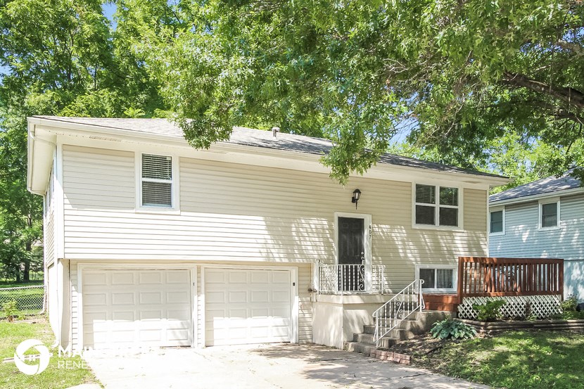 a white house with two garage doors and a porch