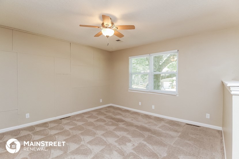 the master bedroom has a large window and carpeted flooring
