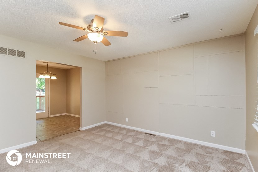 the spacious living room with ceiling fan and tile flooring