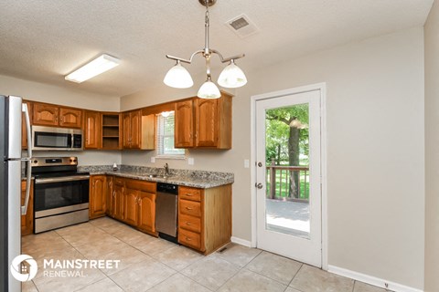 a kitchen with wooden cabinets and a door to a patio