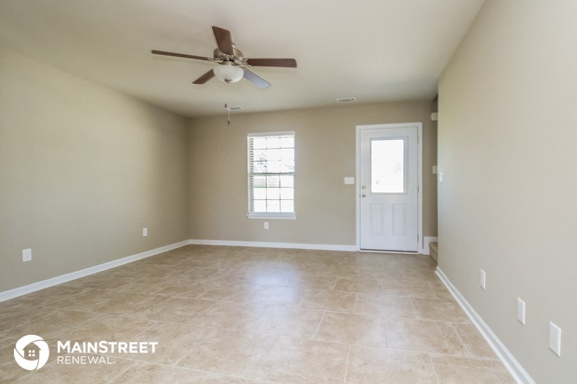 an empty living room with a ceiling fan and a white door
