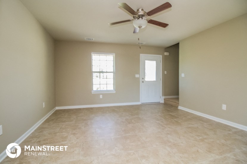 an empty living room with a ceiling fan