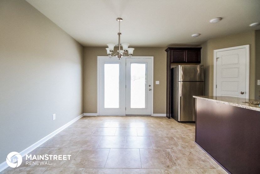 an empty kitchen with a stainless steel refrigerator and a door