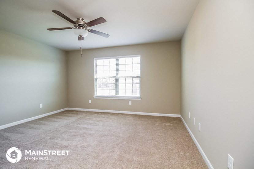 an empty room with a ceiling fan and a window