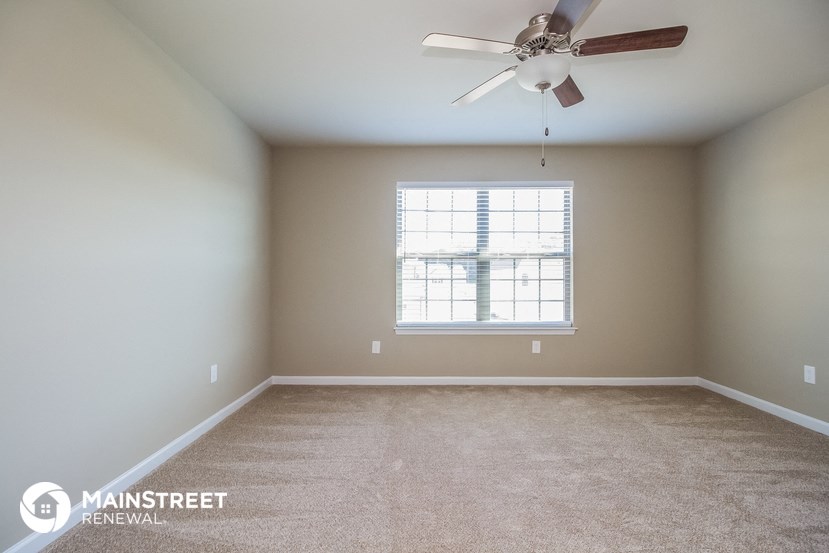 an empty room with a ceiling fan and a window