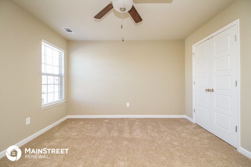 the master bedroom has a carpeted floor and a ceiling fan