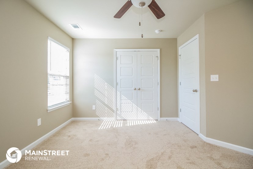 a bedroom with a white door and a ceiling fan