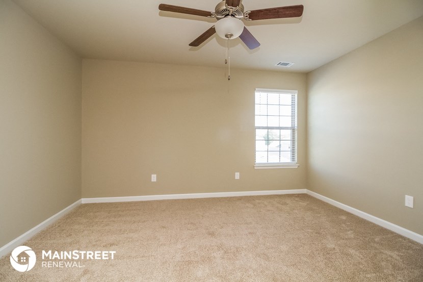 a empty carpeted room with a ceiling fan