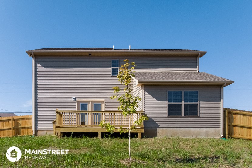 a house with a deck and a tree in front of it