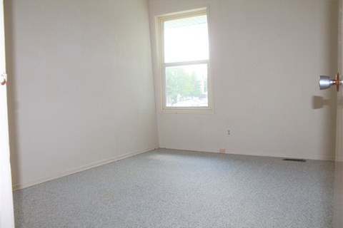 an empty room with a window and white walls