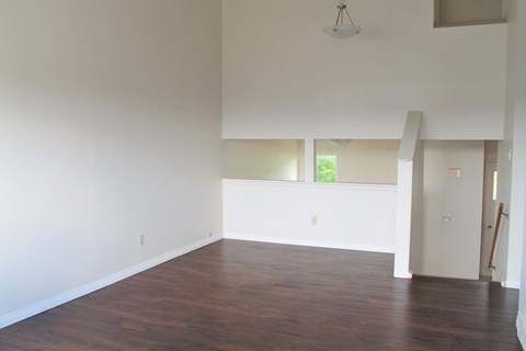 an empty living room with wood floors and white walls
