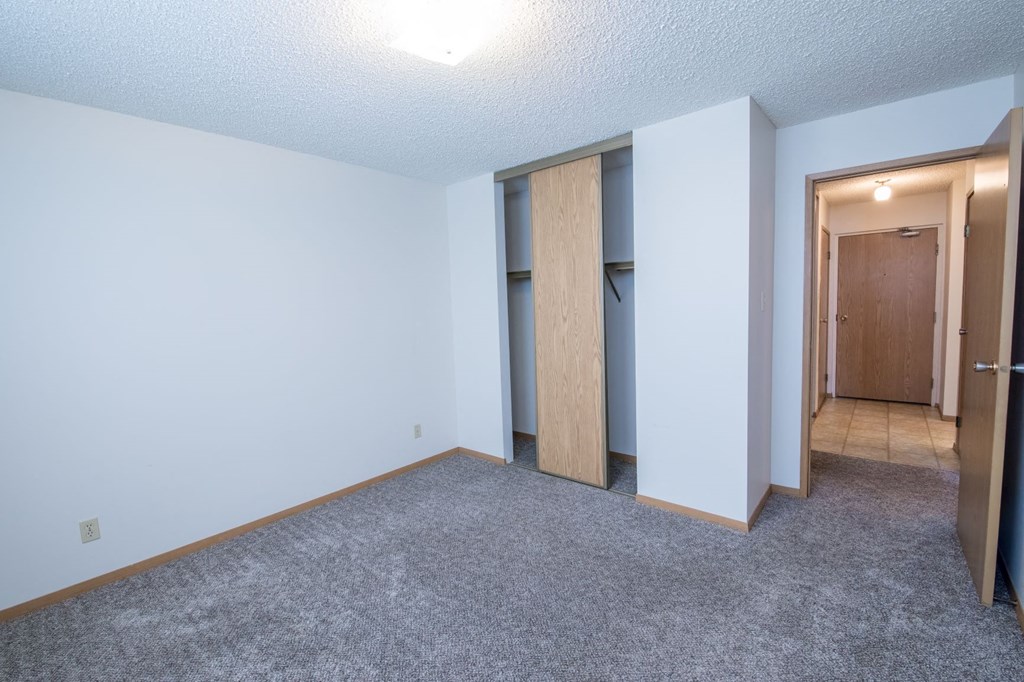a bedroom with a carpeted floor and a door to a closet
