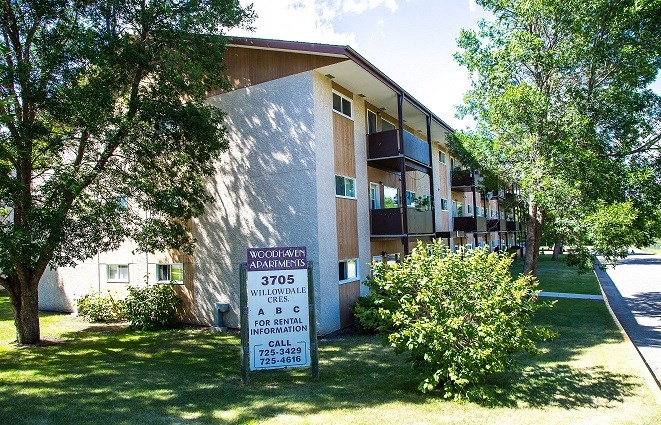 an apartment building with a sign in front of it