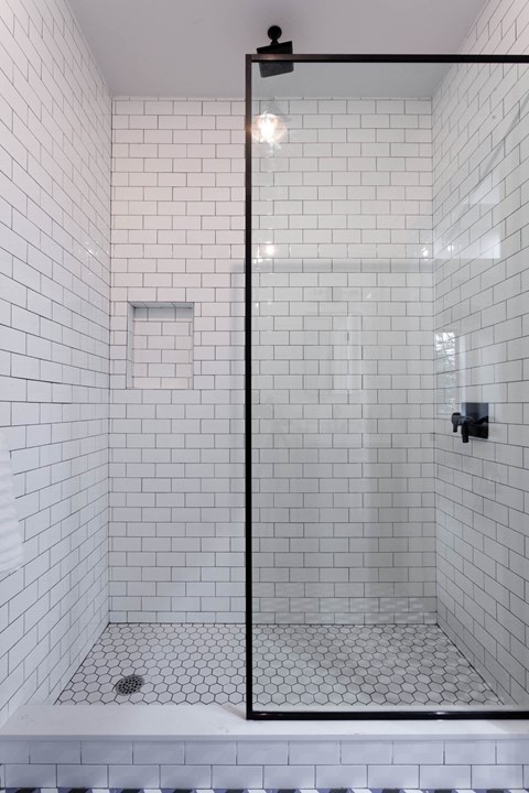 A white tiled shower with a black frame.