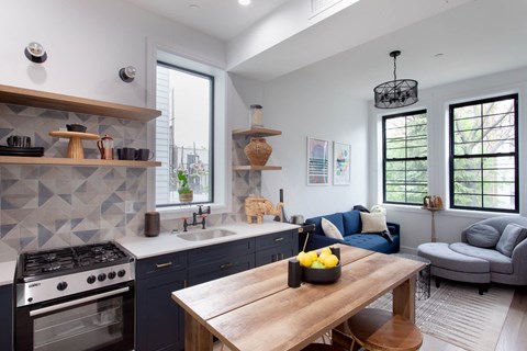 A modern kitchen with a wooden table and a blue couch.