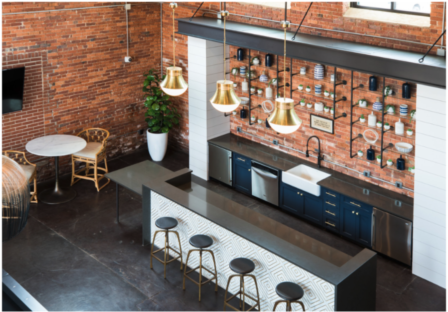 a kitchen with a long counter and stools in front of a brick wall