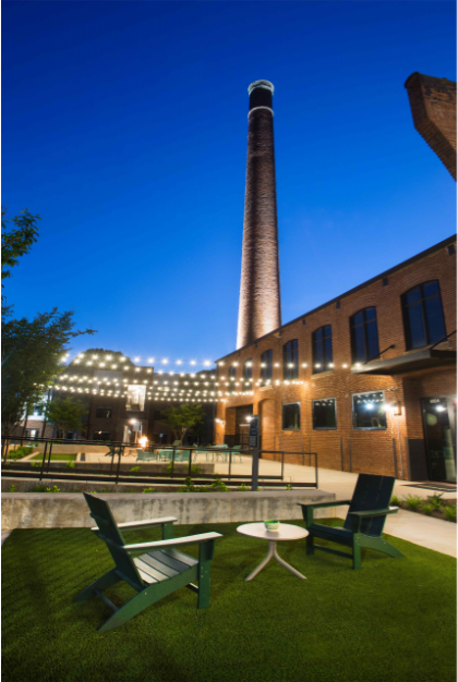 the building is lit up at night with picnic tables