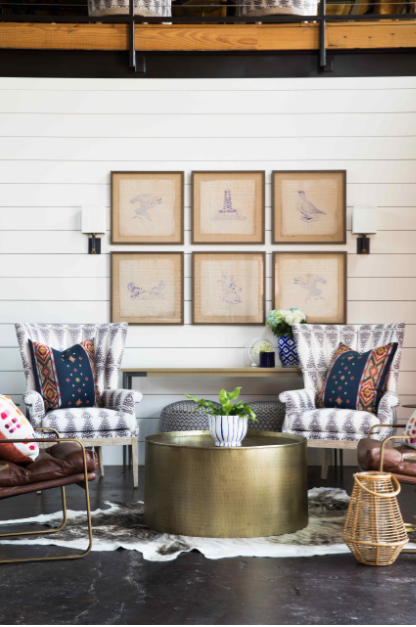 a living room with chairs and a table and pictures on the wall