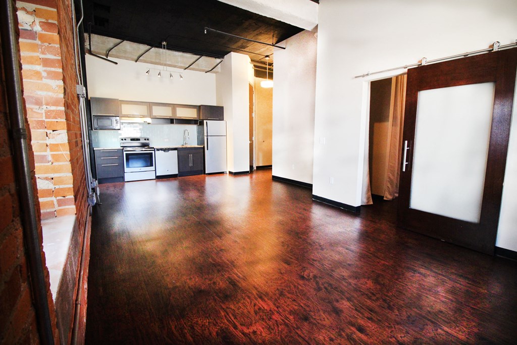 an empty room with wood floors and a kitchen