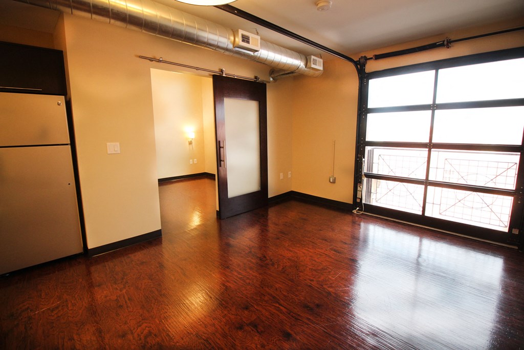 an empty living room with wood floors and a window