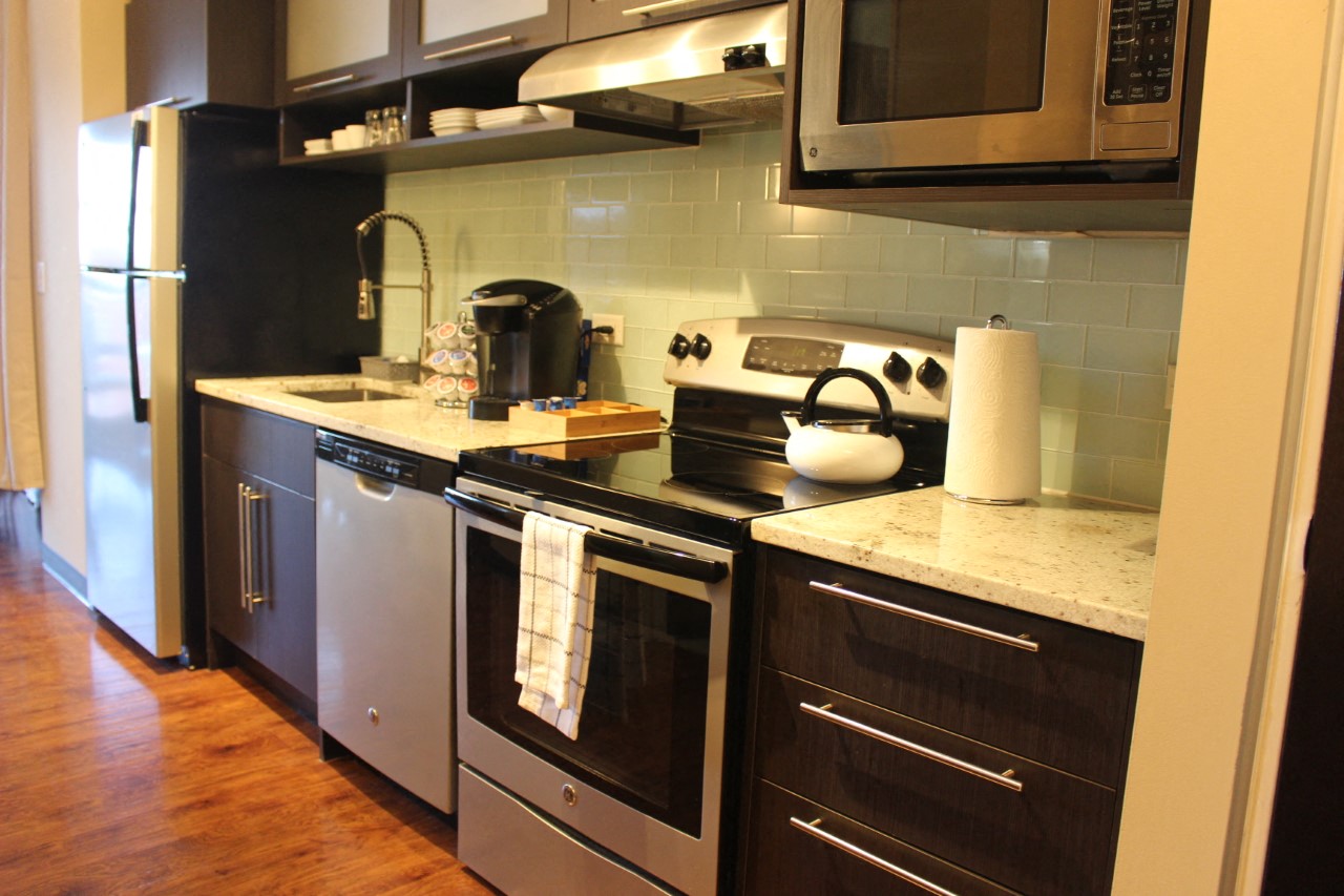 a kitchen with stainless steel appliances and a counter with a tea kettle and a refrigerator