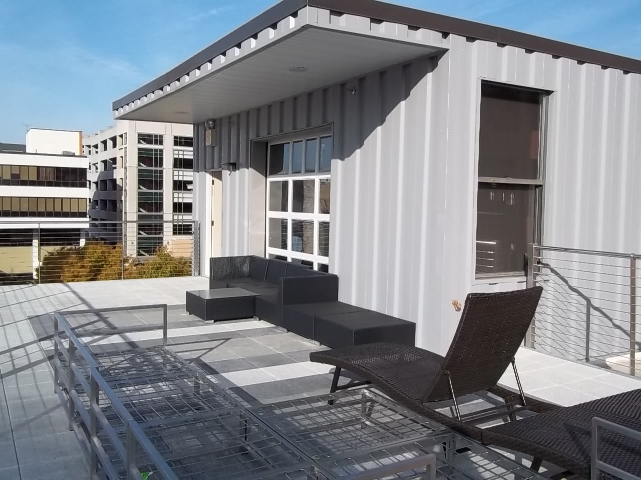 a roof terrace with two chairs and a balcony with a building in the background