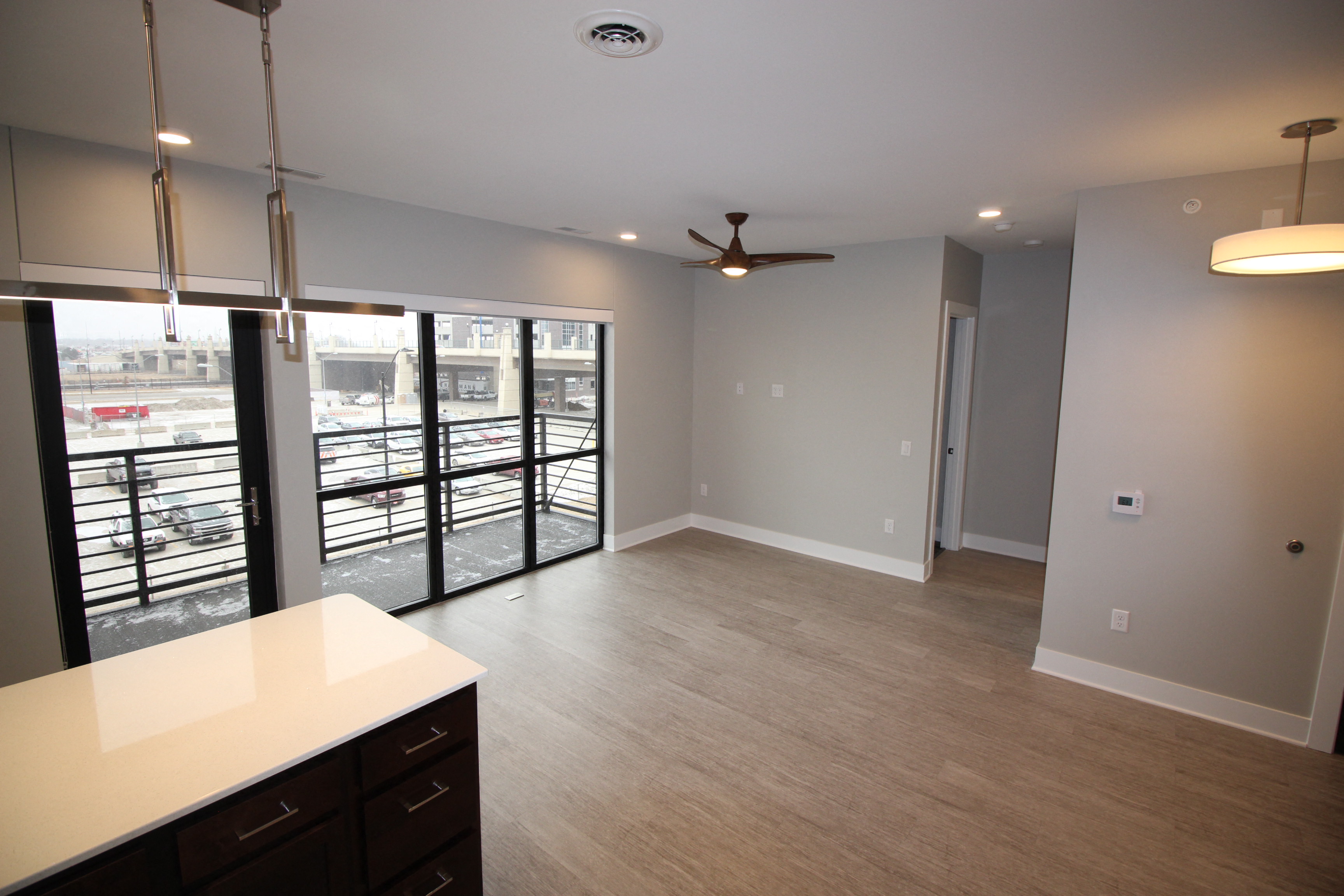 a kitchen and living room with a balcony and a ceiling fan