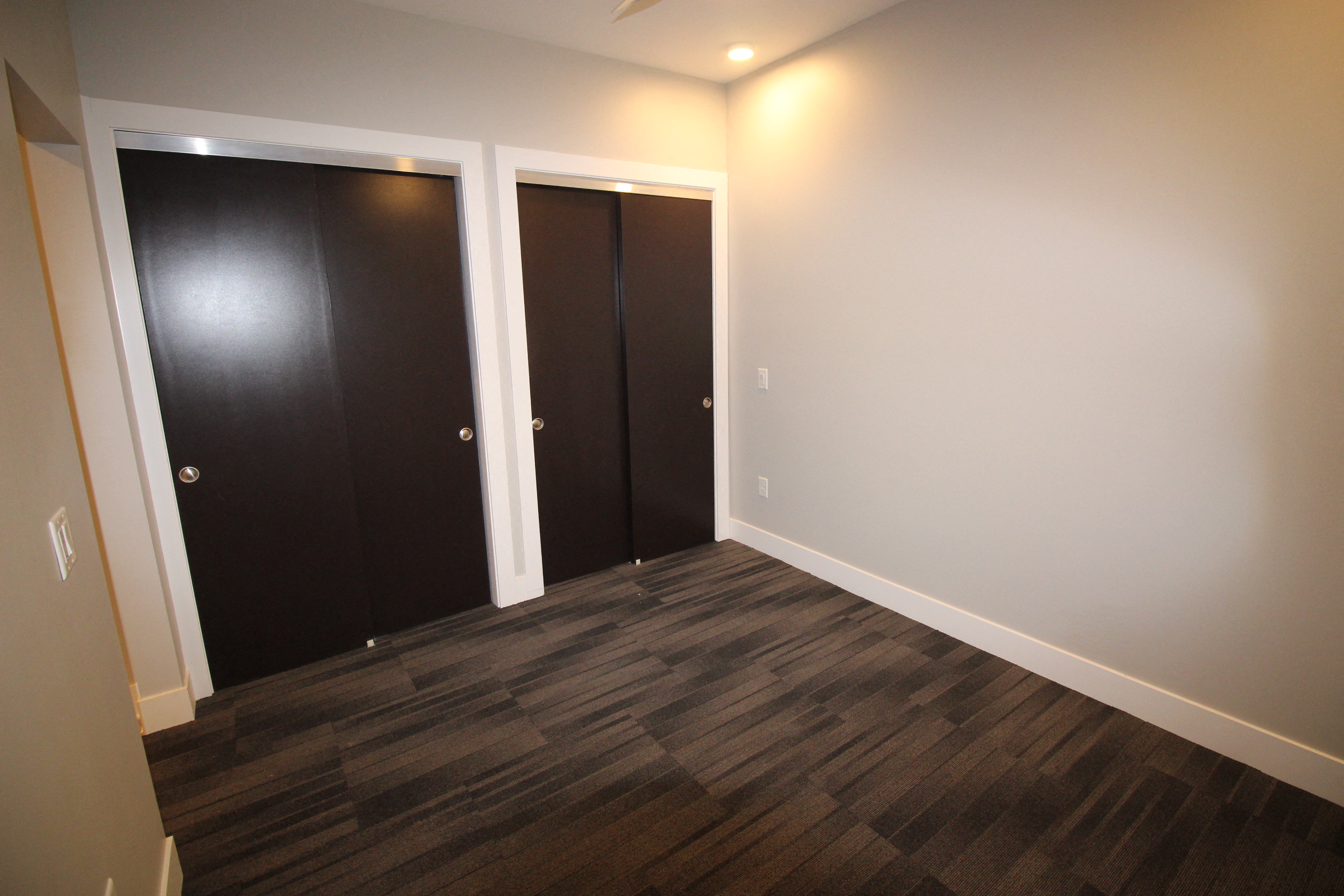 a room with three doors and a hard wood floor