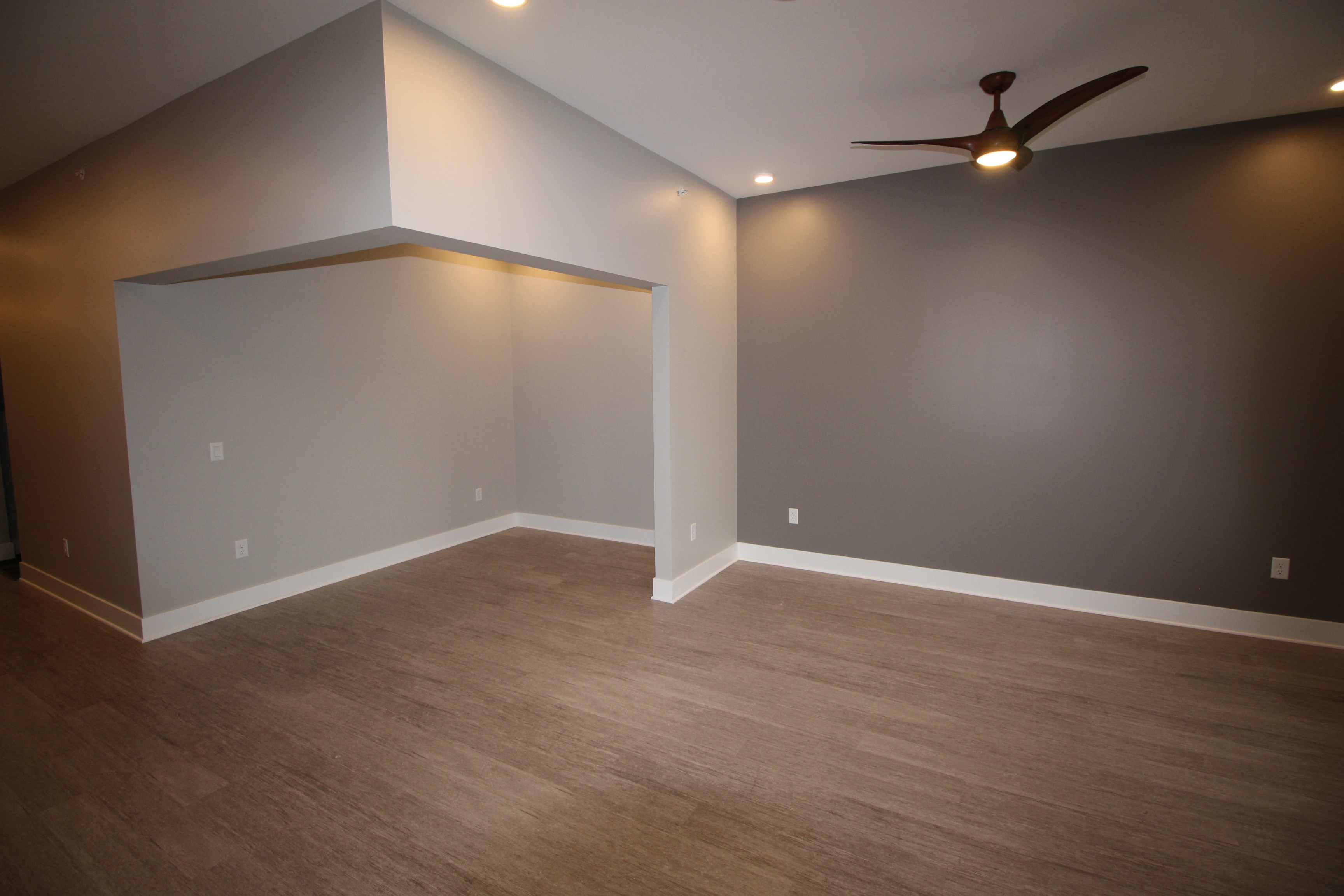 an empty living room with wood floors and a ceiling fan