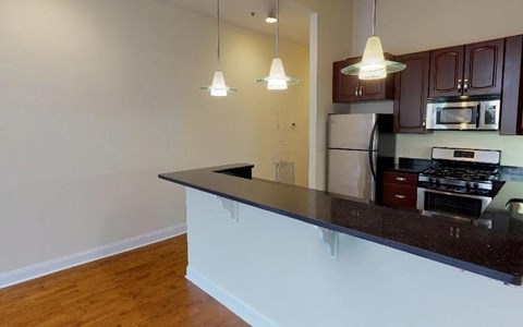 A kitchen with dark brown cabinets and a black countertop.