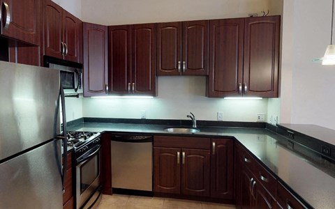 A kitchen with dark wood cabinets and stainless steel appliances.