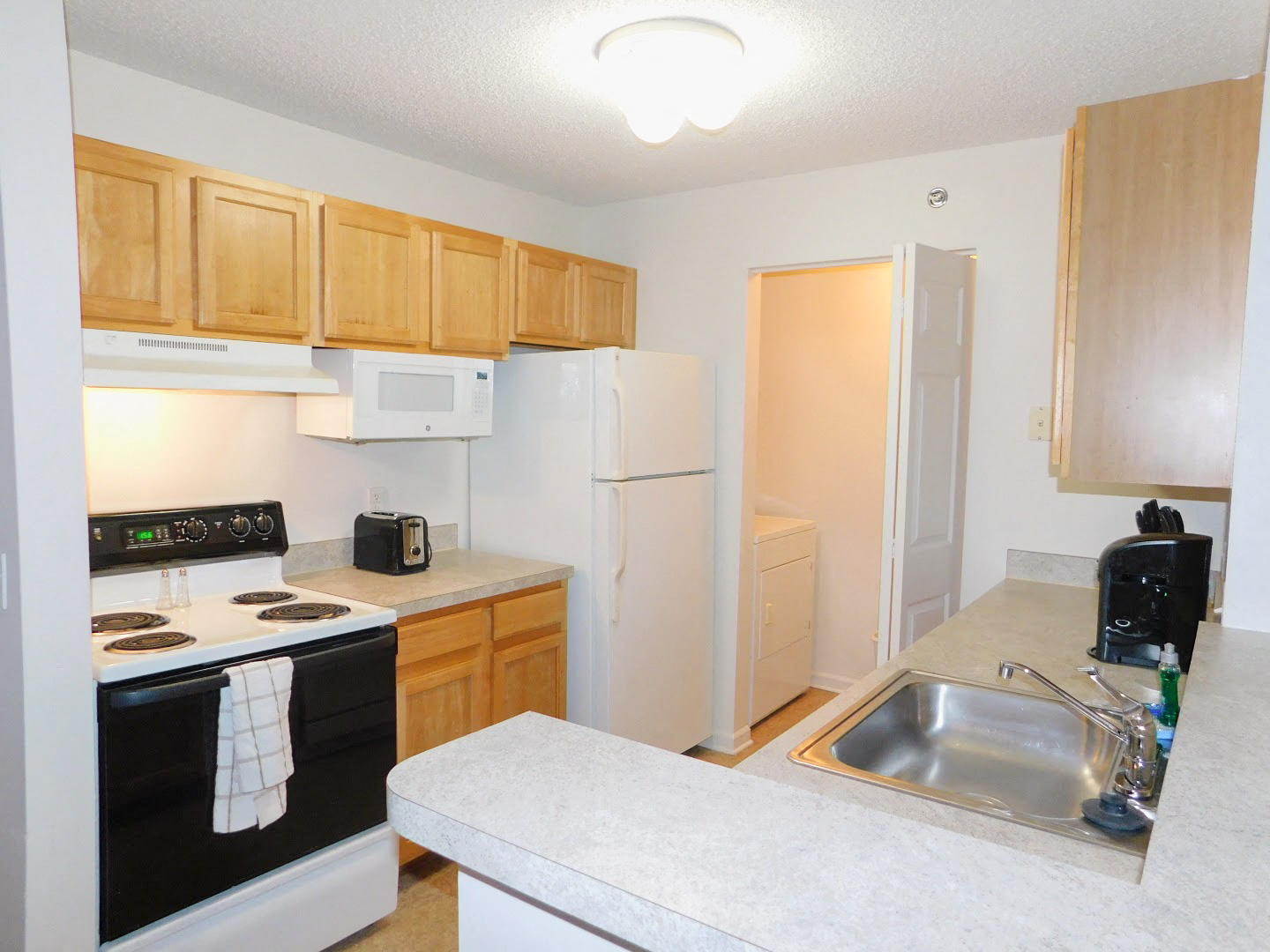 a kitchen with white appliances and wooden cabinets and a sink