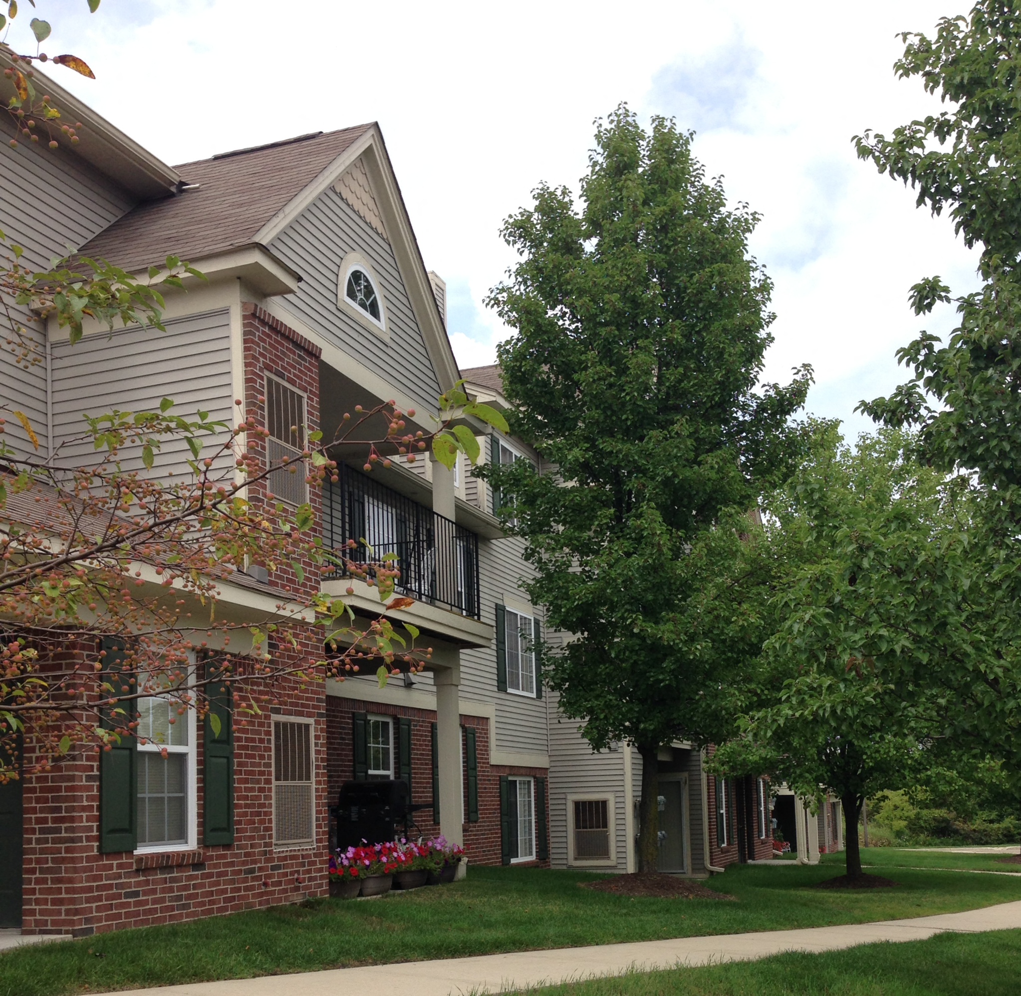 the exterior of an apartment building with trees and a sidewalk