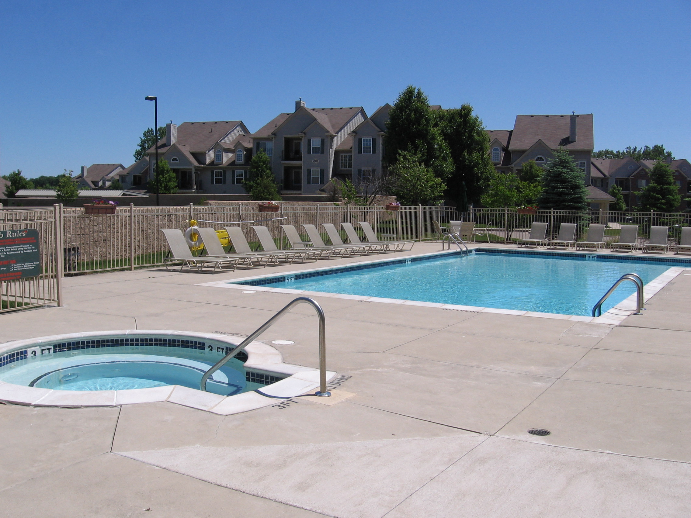 a swimming pool with chairs around it and a house in the background