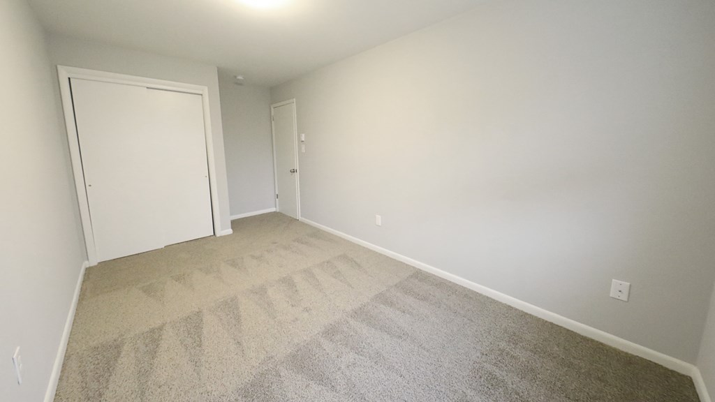 a empty room with a carpeted floor and a white door