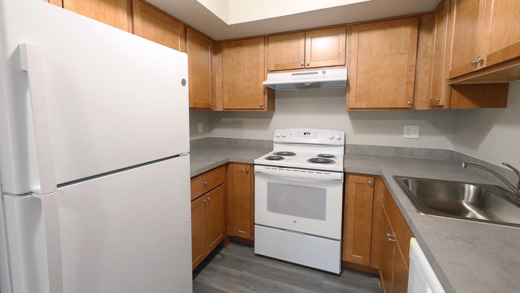 an empty kitchen with wooden cabinets and white appliances
