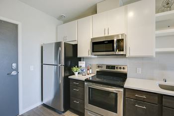 Kitchen with white upper cabinets and brown lower cabinets and stainless steel appliances