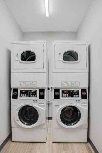Two side by side stacked washers and dryers in laundry room
