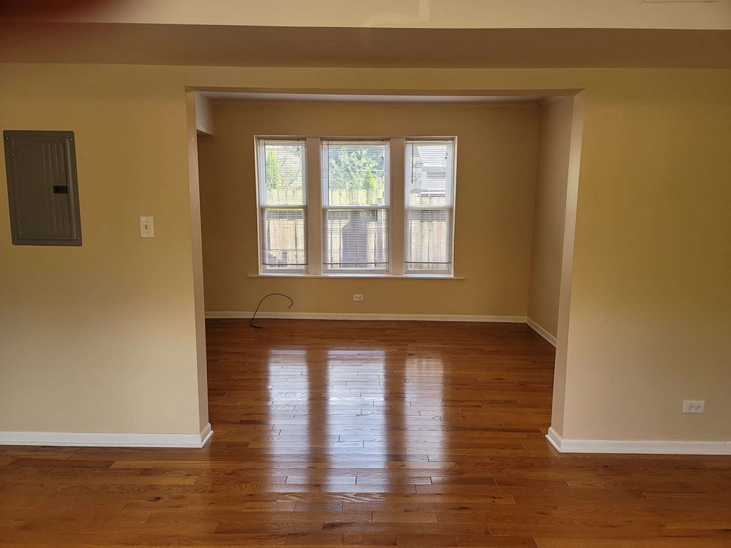 an empty living room with wooden floors and a window