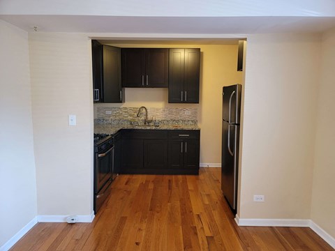 a kitchen with black cabinets and a wood floor