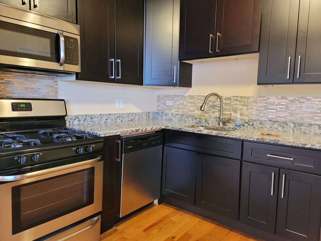 a kitchen with black cabinets and stainless steel appliances