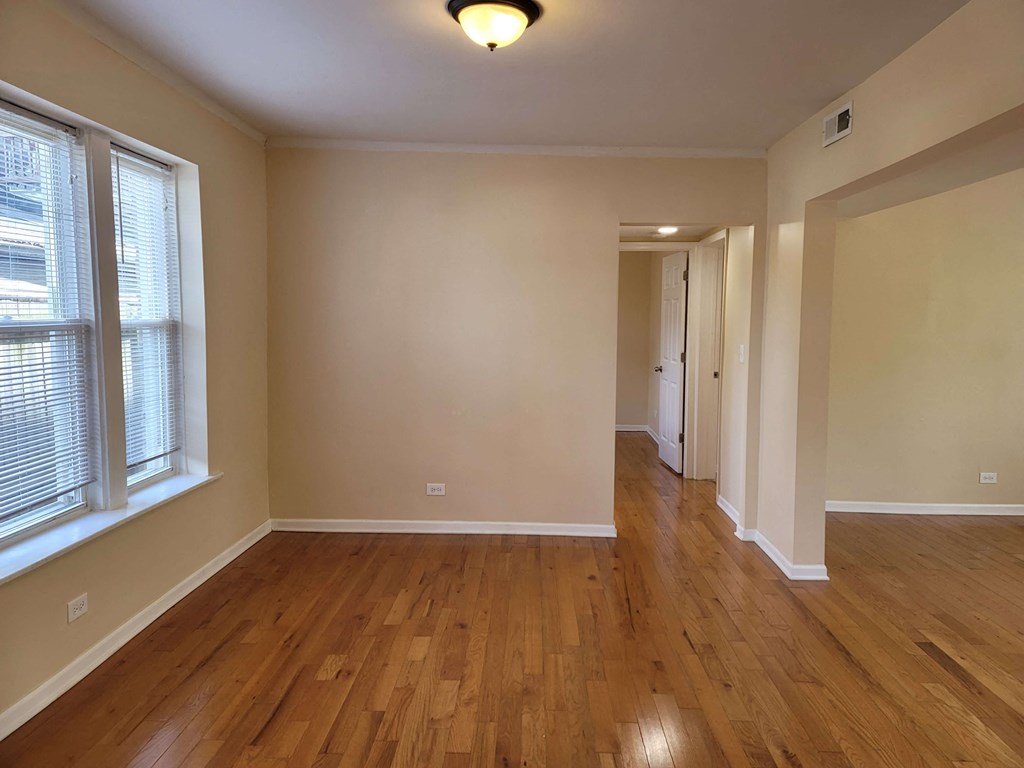 a empty living room with wooden floors and a hallway with windows