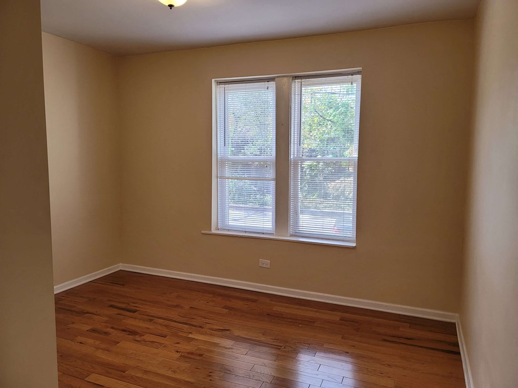 a empty room with a window and wooden floors